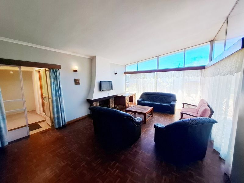 Spacious living room featuring original parquet flooring, a built-in fireplace, and expansive windows that provide abundant natural light.