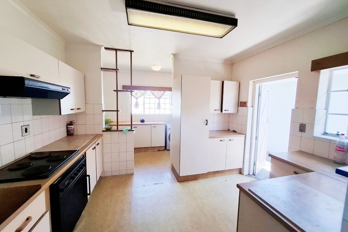 A functional kitchen featuring built-in cabinetry, laminate countertops, and an integrated electric stove with an extractor fan, offering potential for modern renovation.