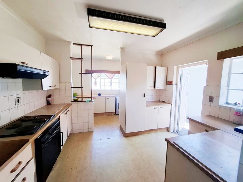 A functional kitchen featuring built-in cabinetry, laminate countertops, and an integrated electric stove with an extractor fan, offering potential for modern renovation.