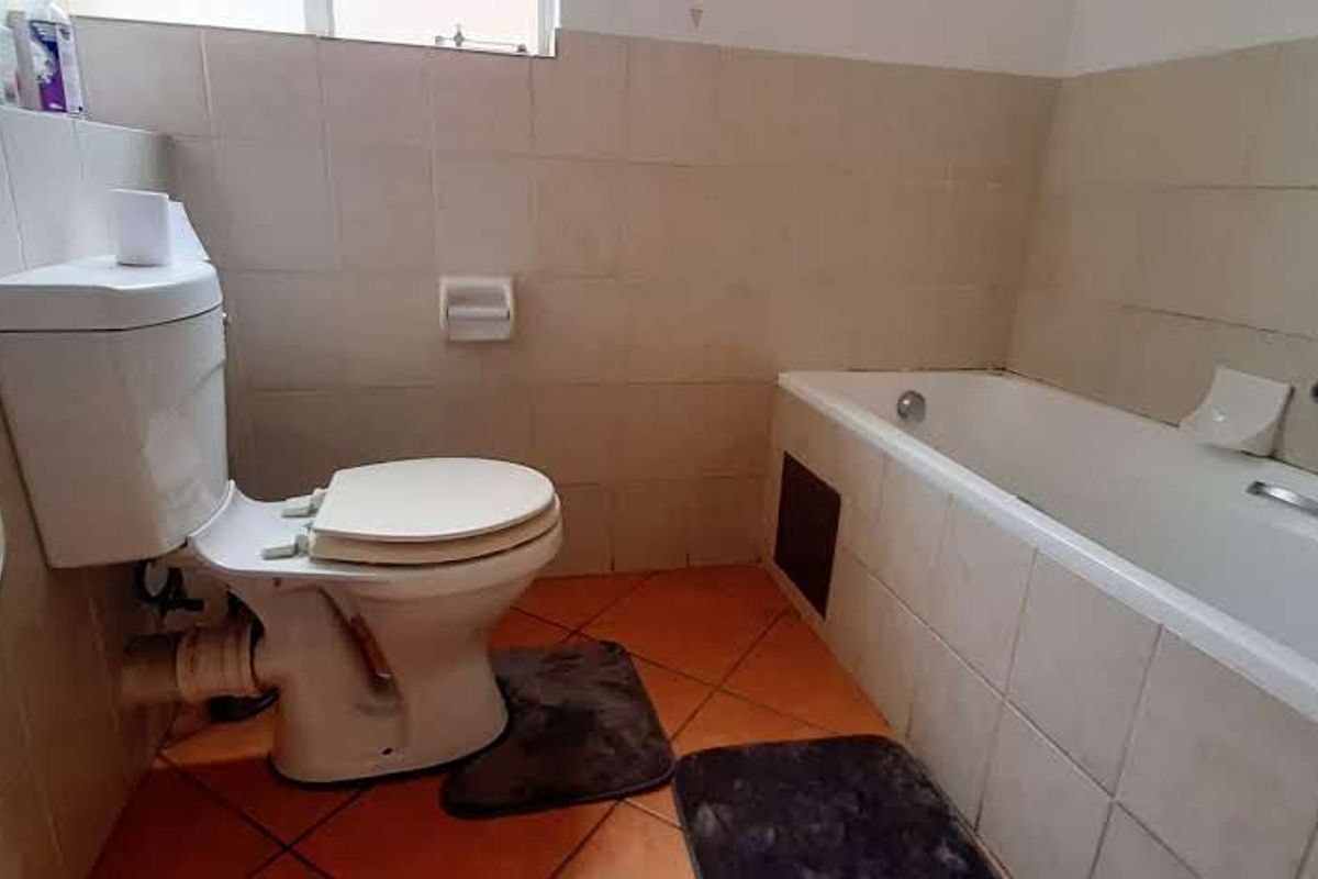 A dated bathroom featuring a standard bathtub, toilet, and basin with tiled finishes, offering potential for a modern renovation.