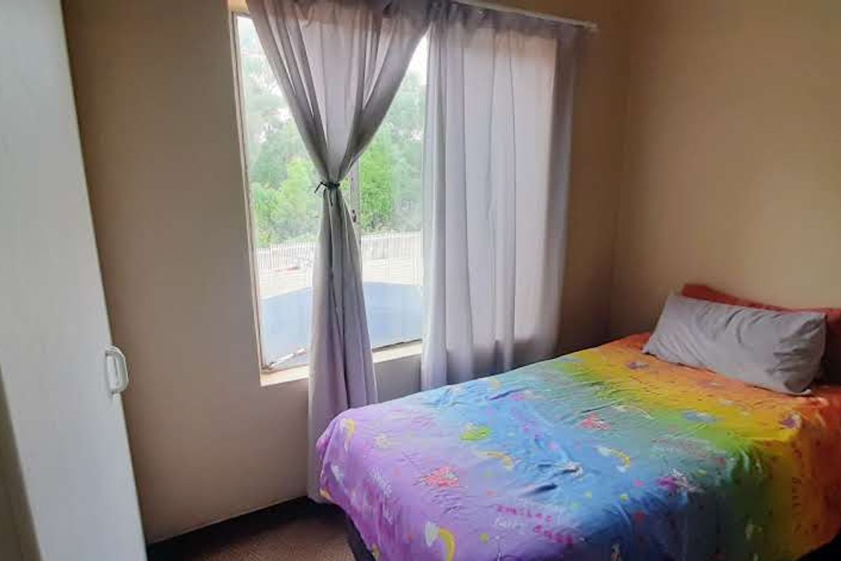 A functional bedroom featuring a built-in wardrobe and natural light from a window.