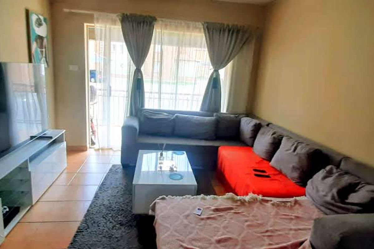 A comfortable living room featuring tiled flooring and a sliding glass door that provides natural light and access to the exterior.