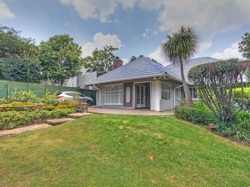 A view of the rear exterior of the house featuring a tiled roof, paved patio area, and a well-maintained garden.