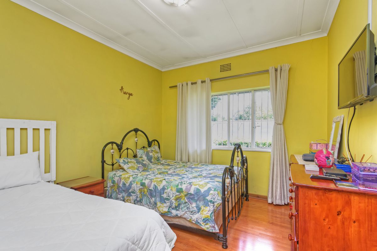 A bedroom featuring timber flooring, a window with security bars, and coved ceiling detailing.
