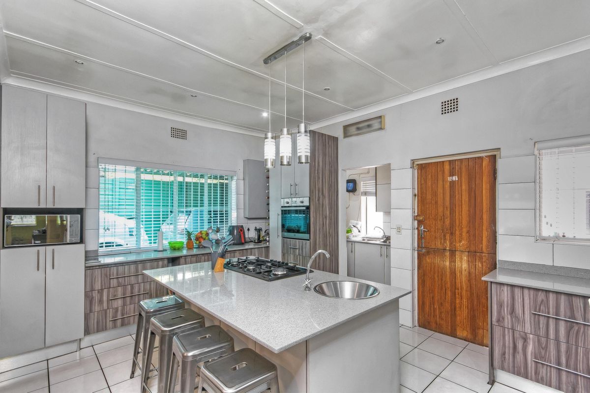 Modern kitchen featuring a central island with a built-in gas hob and sink, complemented by sleek cabinetry and tiled flooring.
