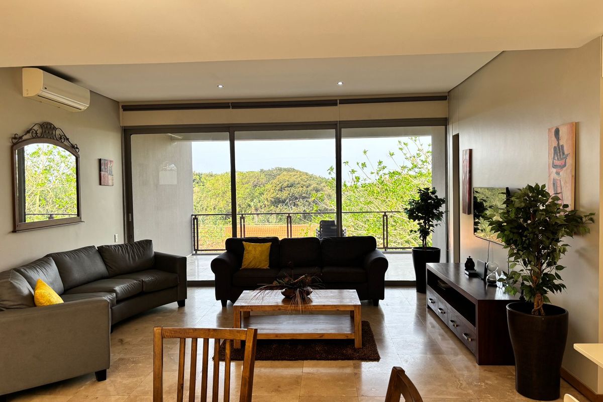 Spacious living room featuring tiled flooring, recessed lighting, and large sliding glass doors that open onto a balcony with scenic views.