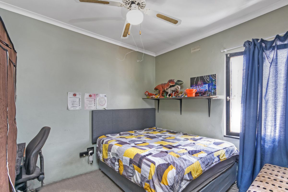 A functional bedroom featuring a ceiling fan, carpeted flooring, and a window with curtain fixtures.