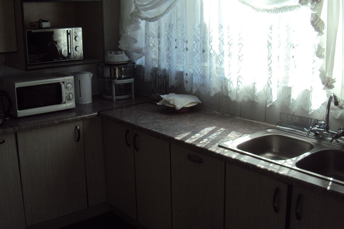A dated kitchen featuring laminate countertops, a double bowl stainless steel sink, and built-in cabinetry with a tiled backsplash.
