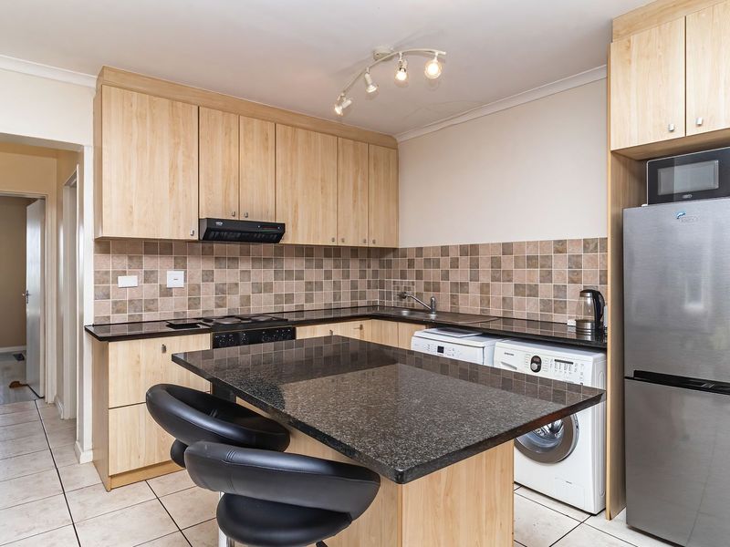 Functional kitchen featuring light wood cabinetry, dark granite countertops, tiled backsplash, and a convenient breakfast nook with integrated appliance space.