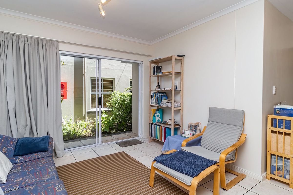 A living room featuring ceramic floor tiles and a sliding glass door providing access to an outdoor area.