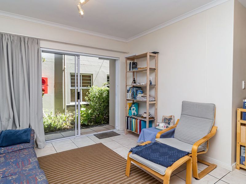 A living room featuring ceramic floor tiles and a sliding glass door providing access to an outdoor area.