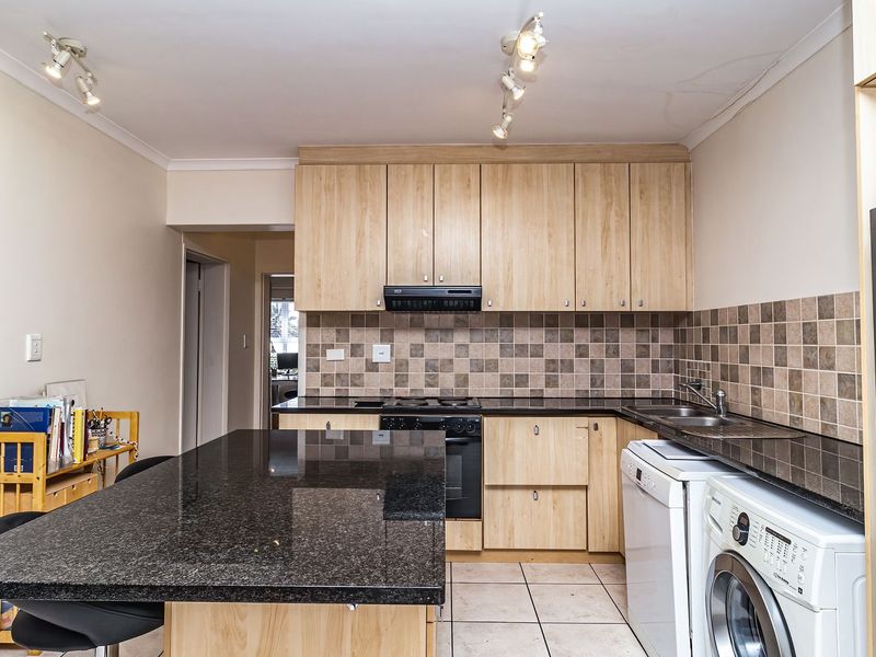 A functional kitchen featuring granite countertops, light wood cabinetry, a central island, and tiled flooring, with integrated appliances and a tiled backsplash.