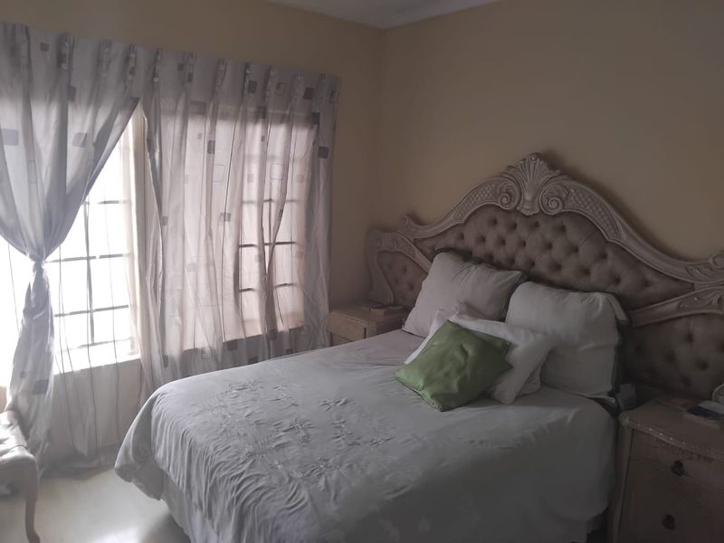 A bedroom featuring a window with security bars and neutral wall finishes.