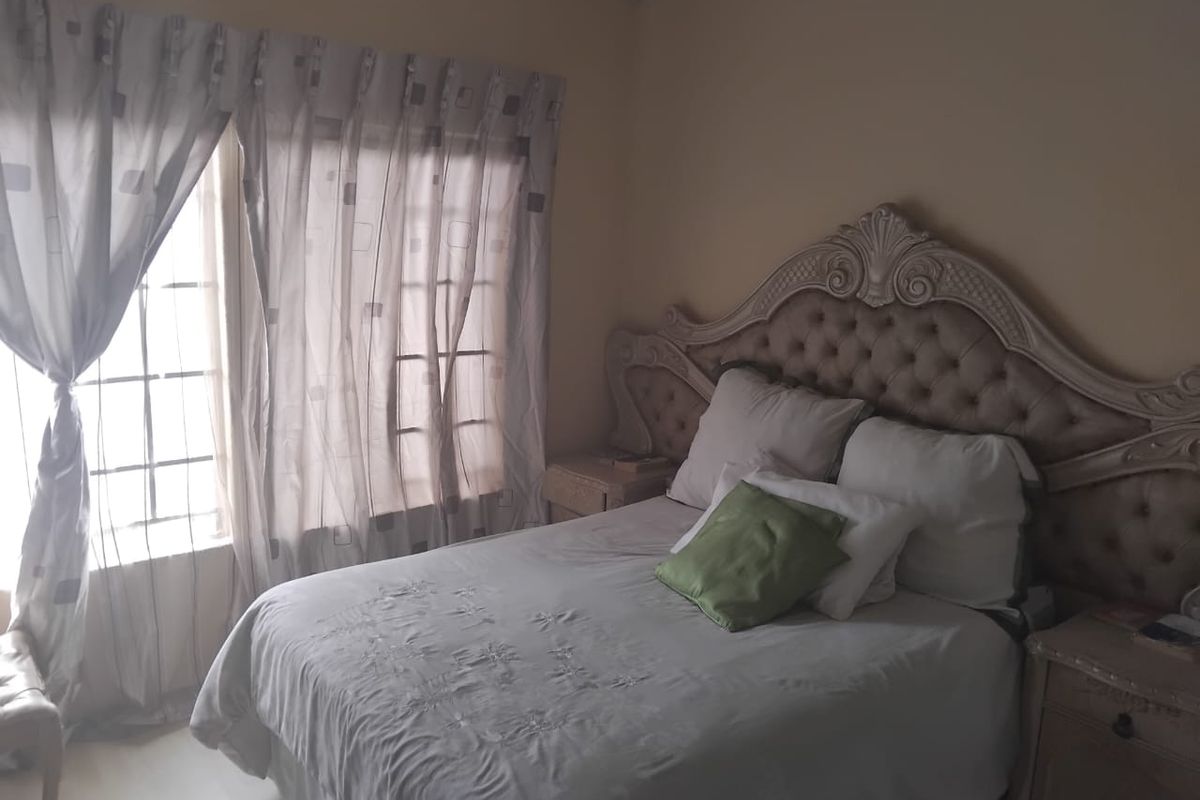 A bedroom featuring a window with security bars and neutral wall finishes.
