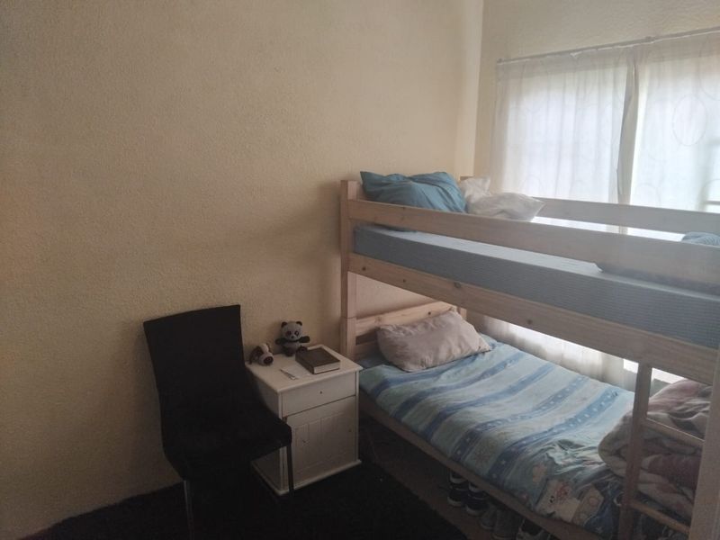 A functional bedroom featuring a window with natural light, suitable for a child or guest room.