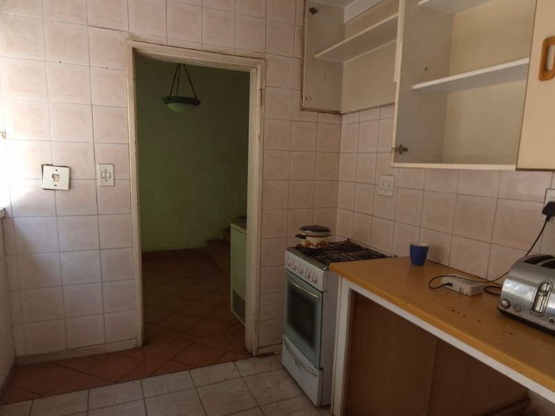 A dated kitchen featuring tiled walls, built-in cabinetry, and a freestanding stove, offering potential for modernization and renovation.