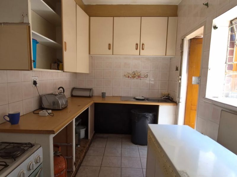 A dated kitchen featuring built-in cabinetry, a gas stove, and tiled splashbacks, offering significant potential for modernization and renovation.