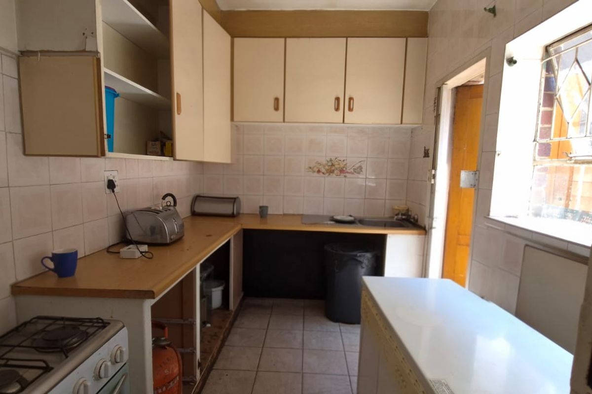 A dated kitchen featuring built-in cabinetry, a gas stove, and tiled splashbacks, offering significant potential for modernization and renovation.