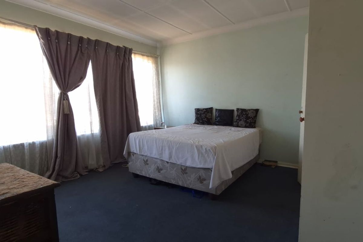 A spacious bedroom featuring large windows that provide ample natural light, finished with carpet flooring and coved ceilings.