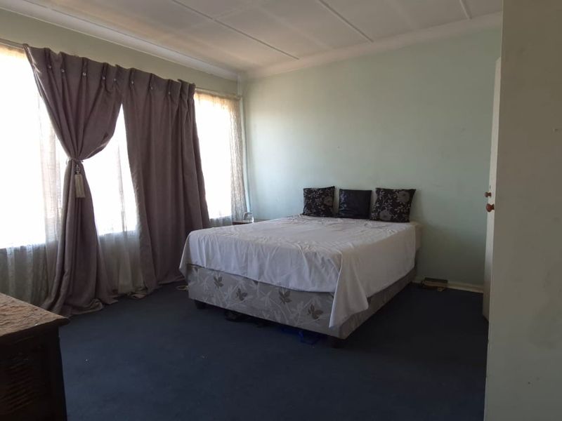A spacious bedroom featuring large windows that provide ample natural light, finished with carpet flooring and coved ceilings.