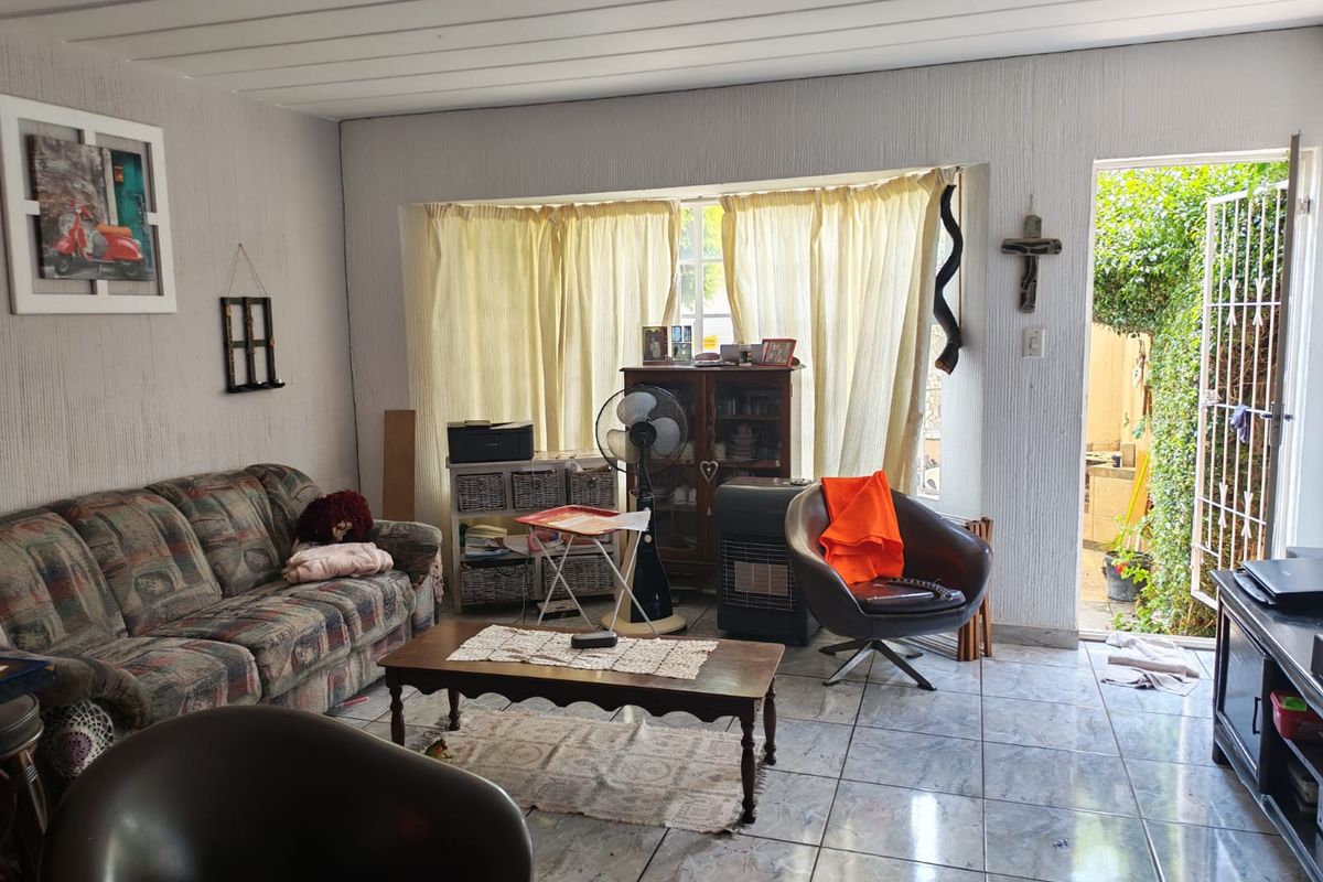 A living room featuring tiled flooring and direct access to an outdoor area through a security gate.