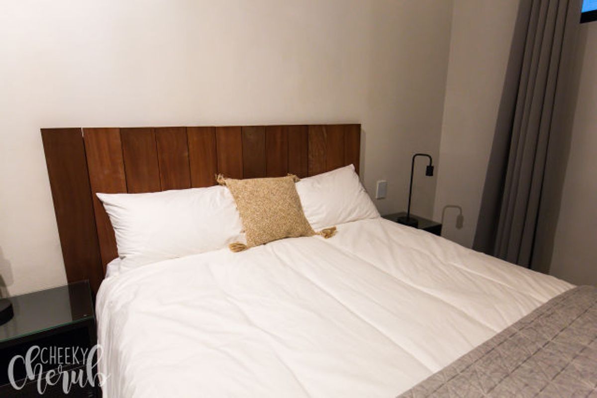 A well-maintained bedroom featuring a custom timber headboard and neutral wall finishes, providing a comfortable and modern sleeping space.
