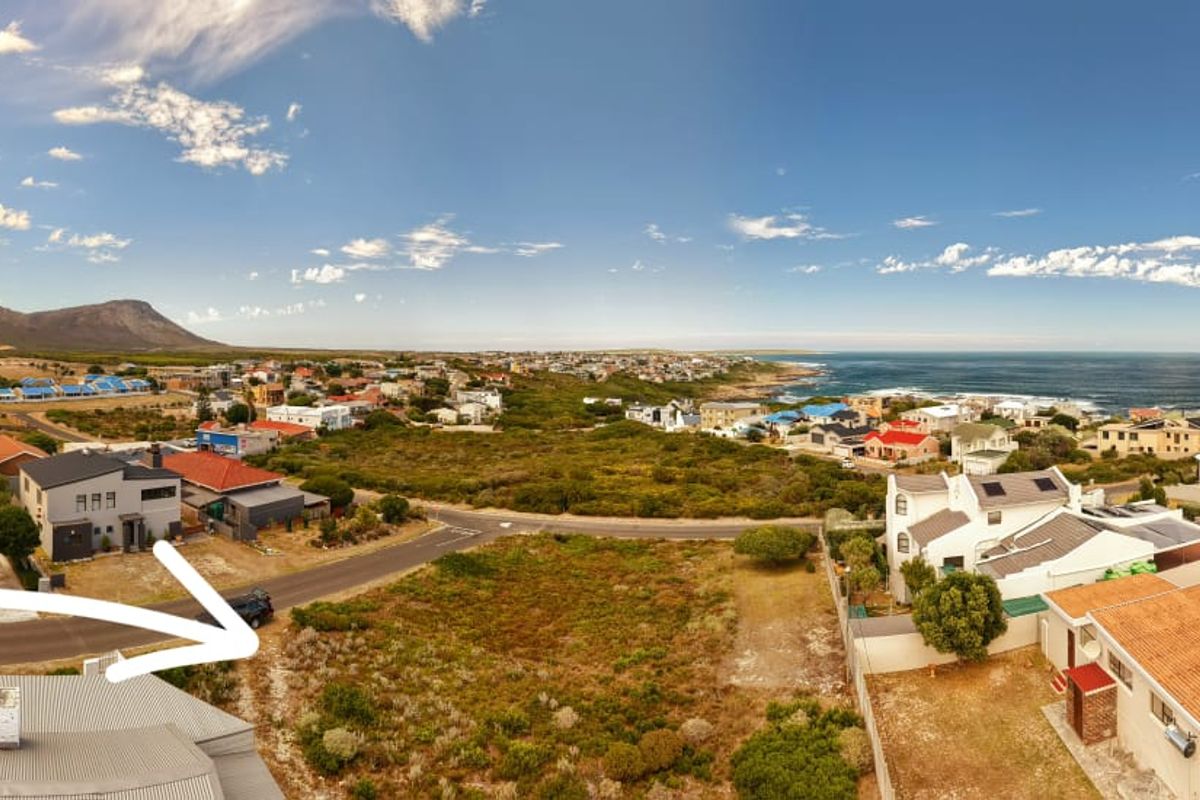 Aerial view of a vacant residential plot situated in a coastal neighborhood with surrounding homes and ocean views.