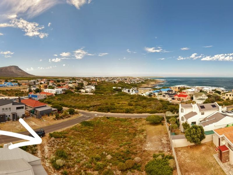 Aerial view of a vacant residential plot situated in a coastal neighborhood with surrounding homes and ocean views.