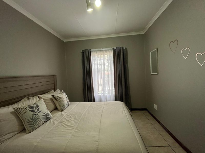 A well-maintained bedroom featuring neutral wall tones, tiled flooring, and a coved ceiling, providing a clean and functional living space.