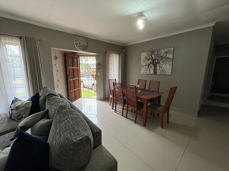 Open plan living and dining area featuring large format floor tiles and direct access to the front exterior through a secure timber door.