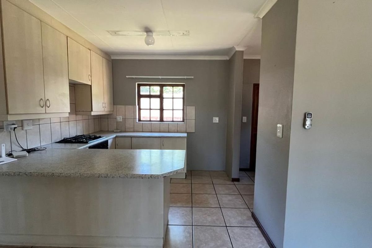 A functional kitchen featuring built-in cabinetry, laminate countertops, a gas hob, and tiled flooring. The space is clean and ready for updates.
