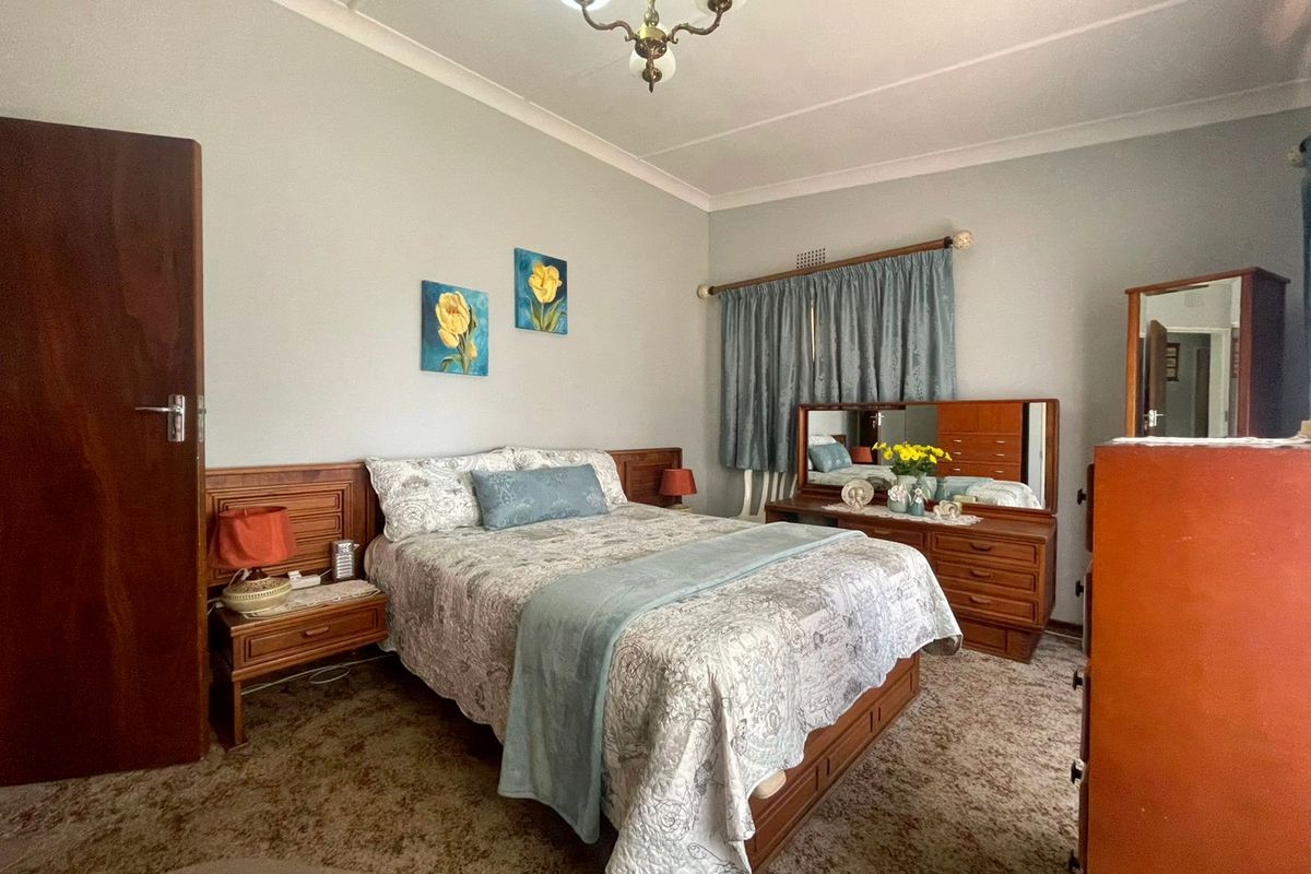 A bedroom featuring carpet flooring, a built-in headboard, and a classic chandelier light fixture.