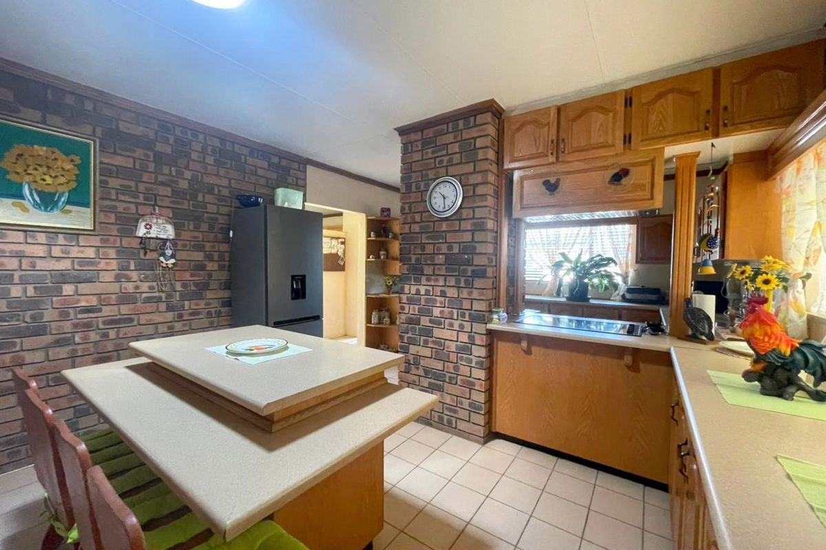 A traditional kitchen featuring exposed brick walls, wooden cabinetry, a central island, and tiled flooring.