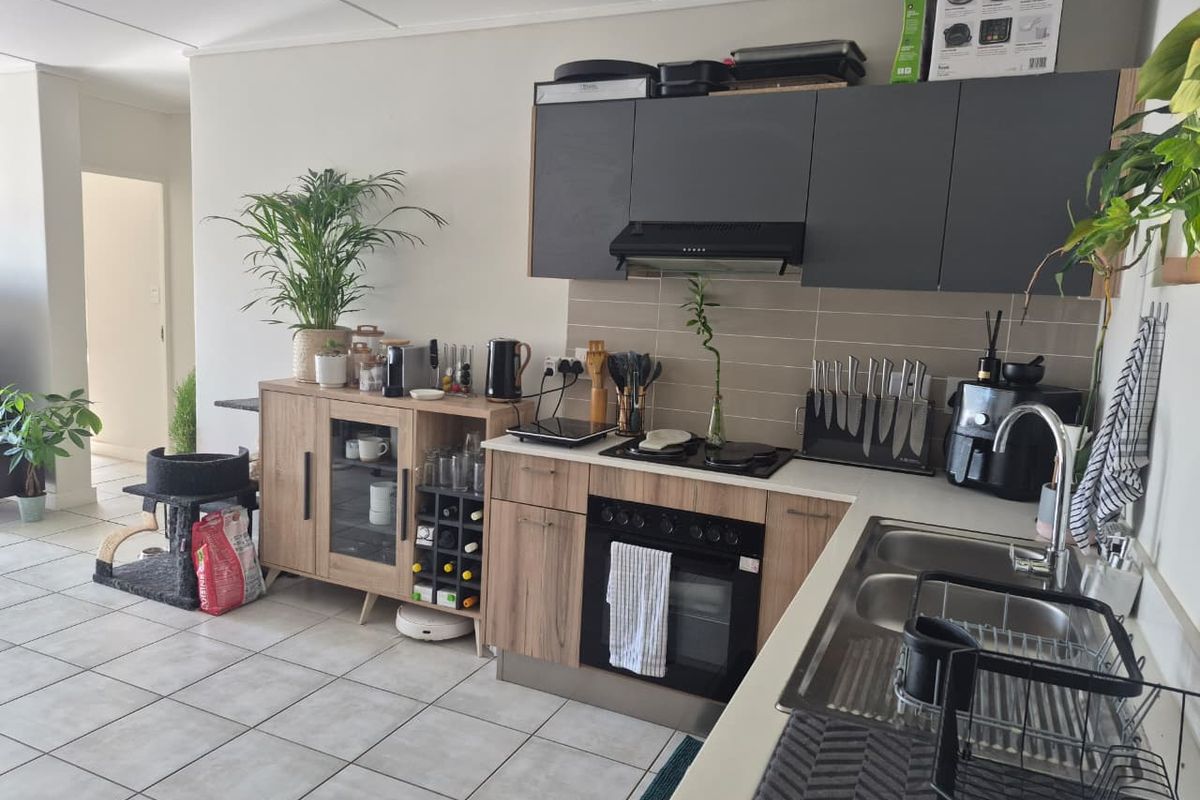 A functional kitchen featuring wood-look lower cabinetry, dark upper cabinets, a built-in oven with hob, and a double sink with tiled backsplash.