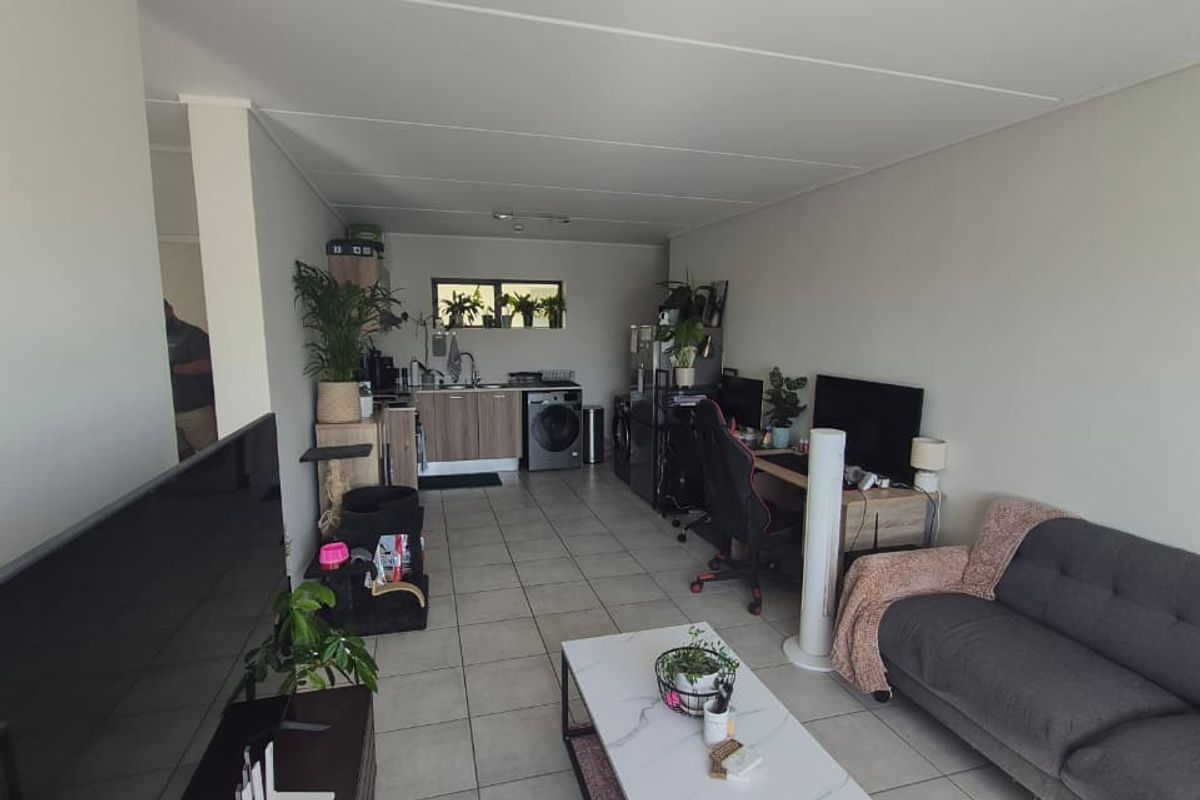 Open plan living area featuring tiled flooring and a functional kitchen space with built-in cabinetry and sink.