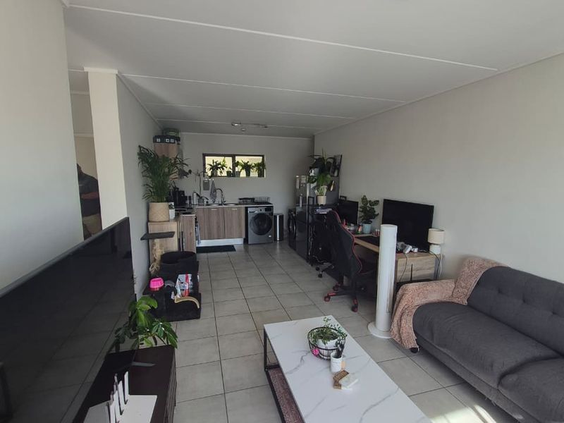 Open plan living area featuring tiled flooring and a functional kitchen space with built-in cabinetry and sink.