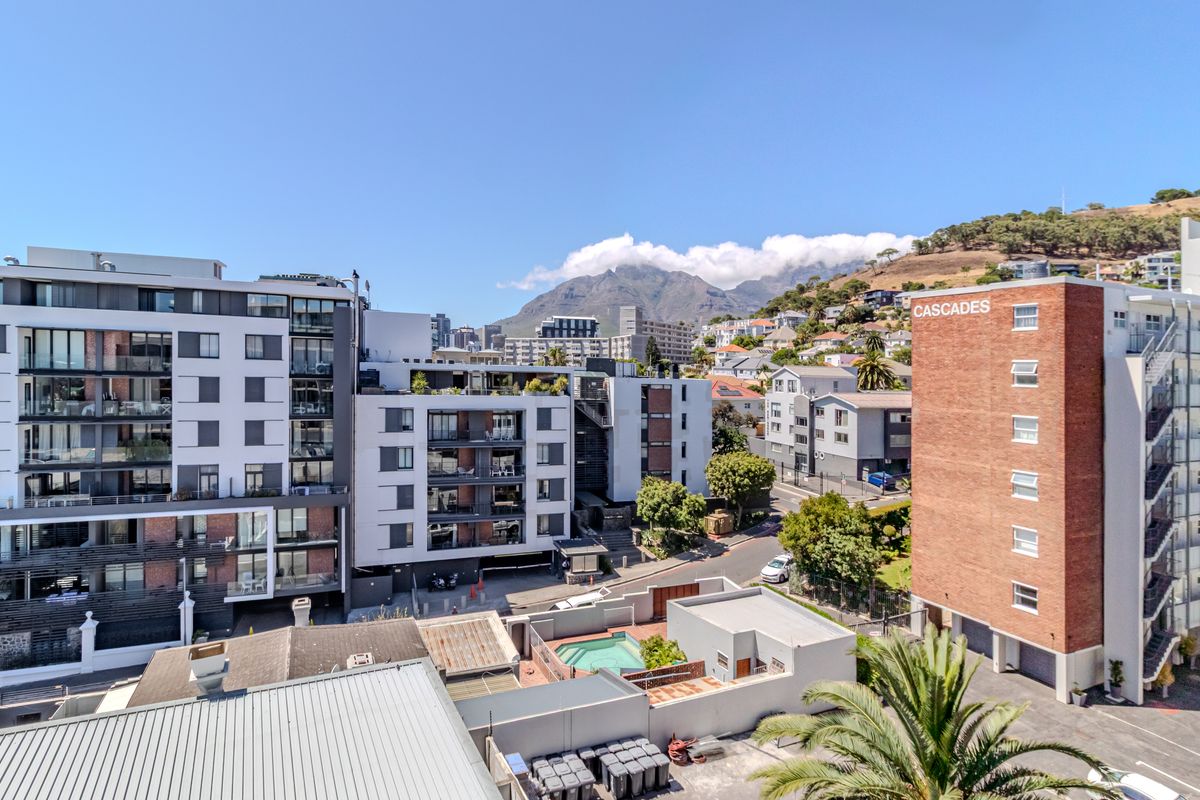Elevated aerial view of the apartment complex, showcasing surrounding urban architecture, mountain backdrop, and local residential landscape.