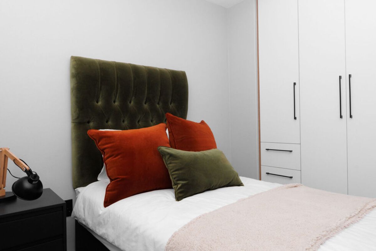A well-maintained bedroom featuring built-in floor-to-ceiling wardrobes with modern hardware and neutral finishes.