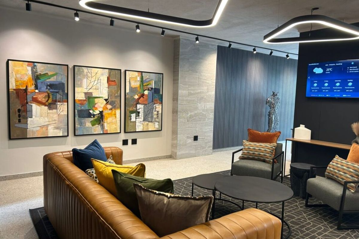 A modern, well-lit lounge area featuring contemporary track lighting, decorative wall paneling, and high-quality stone flooring finishes.