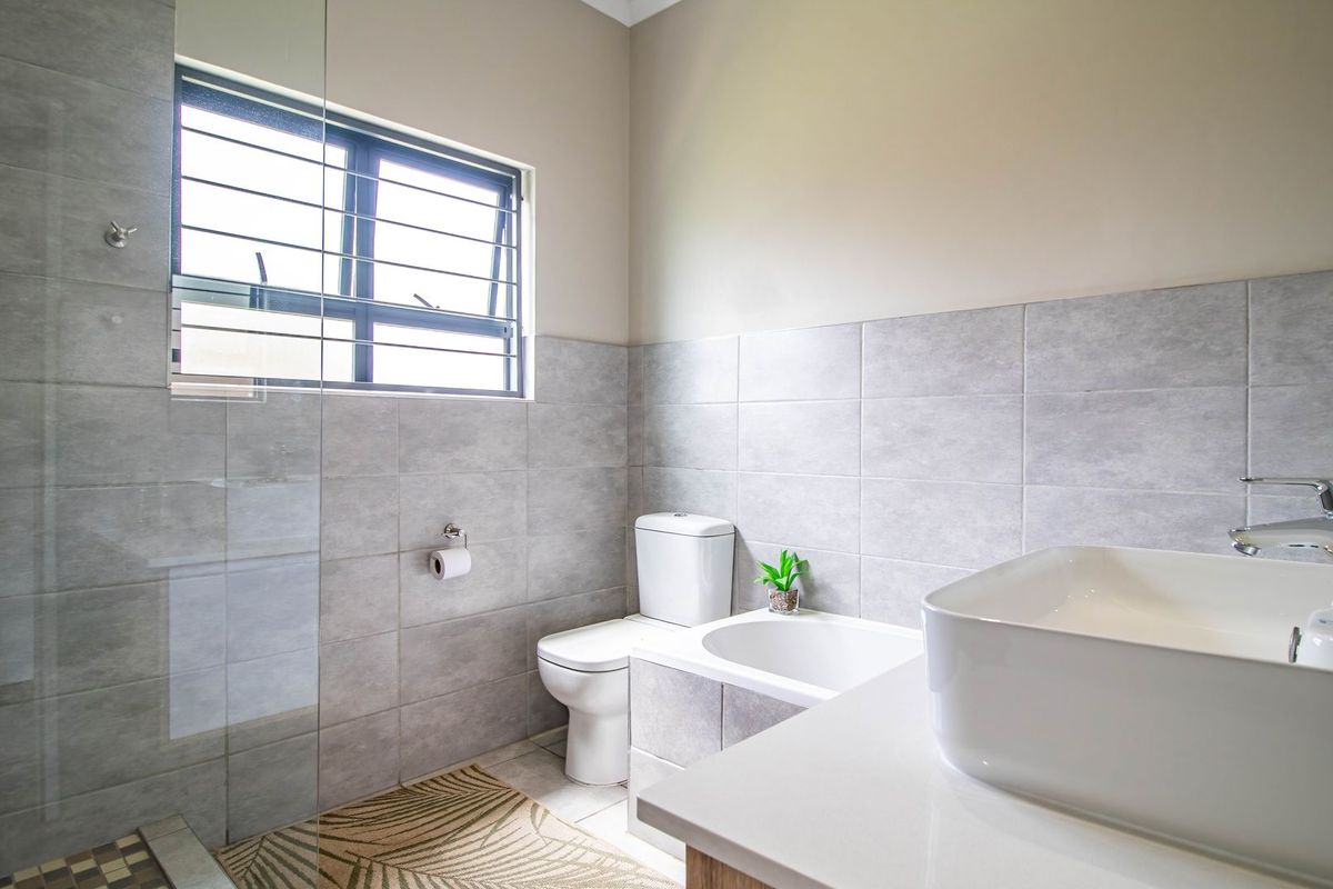 Modern bathroom featuring a glass-enclosed shower, contemporary vessel sink, and neutral grey wall tiling.