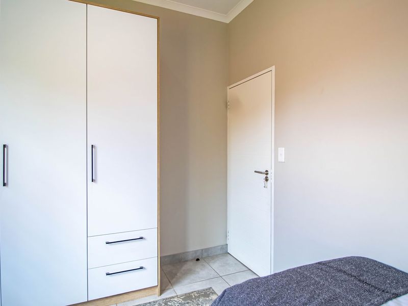 A bright bedroom featuring modern built-in cupboards with clean lines and neutral wall finishes.