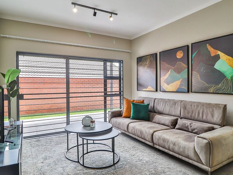 A bright living room featuring large sliding glass doors that open to an outdoor patio area, complemented by modern track lighting.