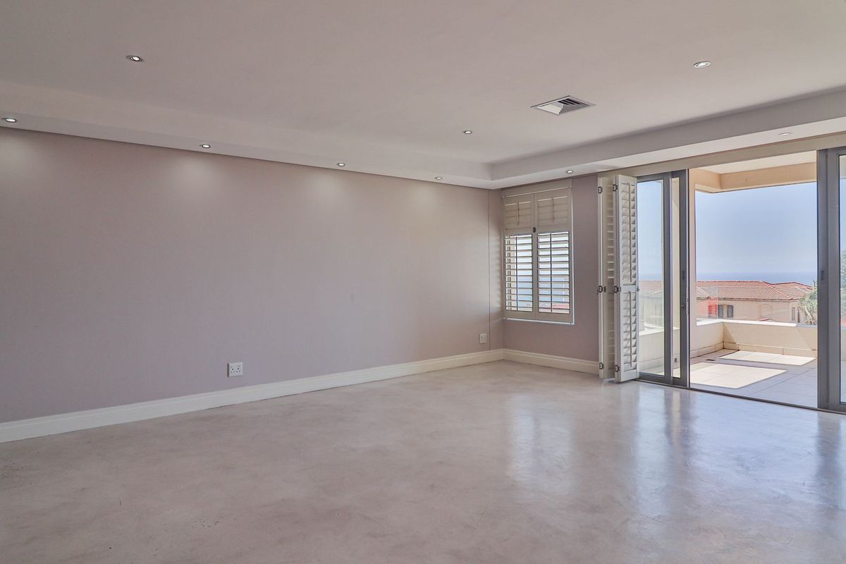 Spacious living area featuring polished concrete floors, recessed downlighting, and large sliding doors opening onto a private balcony with scenic views.