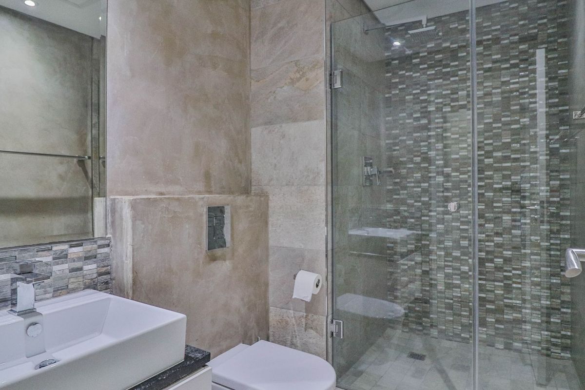 Modern bathroom featuring a glass-enclosed shower with mosaic tile accents, a wall-mounted toilet, and a contemporary vessel sink vanity.