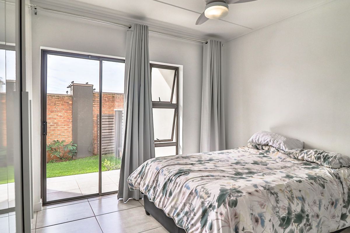 A bright bedroom featuring tiled flooring, a ceiling fan, and a sliding glass door providing direct access to an outdoor patio area.
