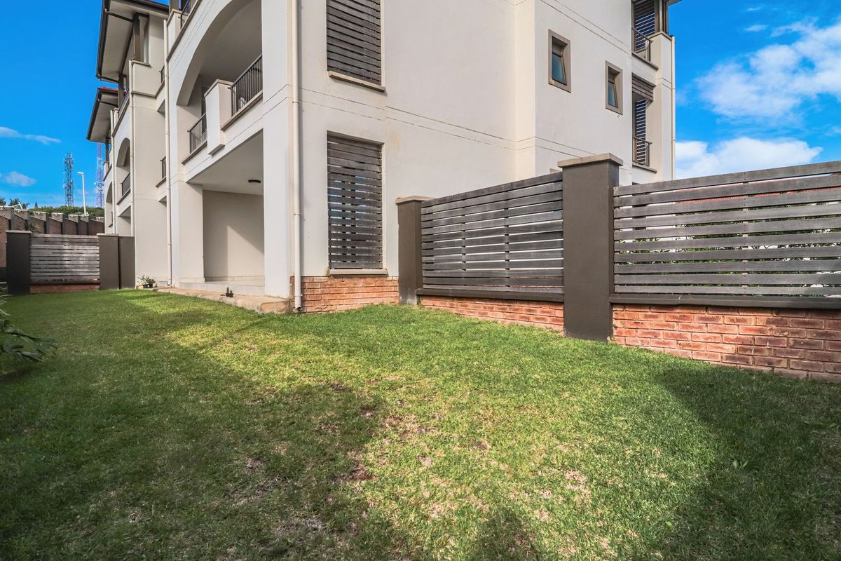 A well-maintained rear garden area featuring a lawn, brick and timber boundary fencing, and access to a covered patio.