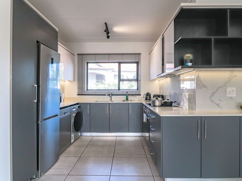 Modern kitchen featuring sleek grey cabinetry, stone countertops, integrated appliances, and high-quality finishes with ample storage and workspace.