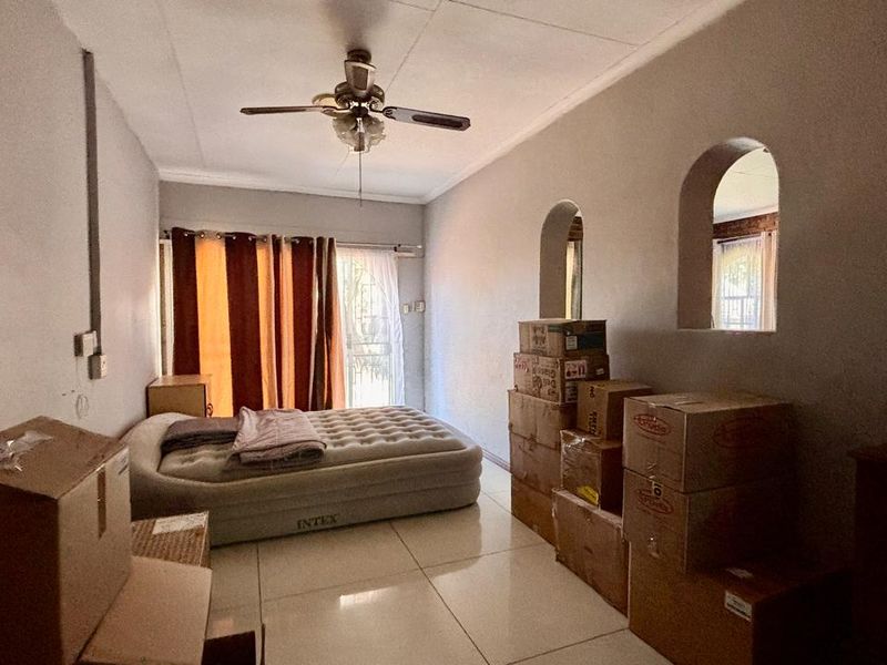 A bedroom featuring tiled flooring, a ceiling fan, and distinctive arched wall niches, currently used for storage.