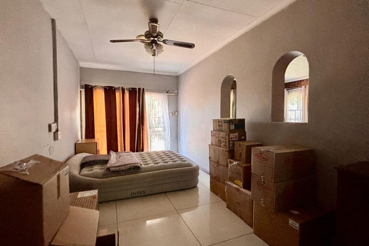 A bedroom featuring tiled flooring, a ceiling fan, and distinctive arched wall niches, currently used for storage.