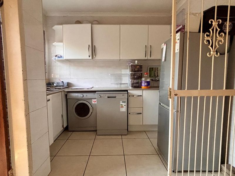 A functional scullery area featuring tiled flooring, built-in cabinetry, and dedicated space for laundry and kitchen appliances.